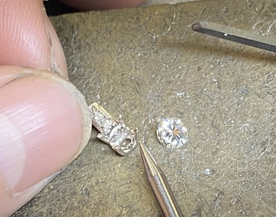 ダイヤモンドをペンダント枠に合わせて石留め前確認している工程