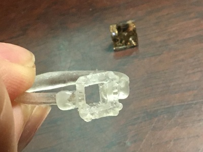 リング原型の石座部分を上から見た写真と後ろに置かれたダイヤモンド