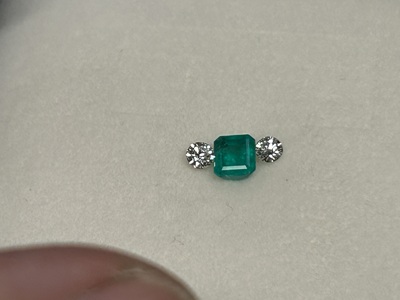 エメラルドを中央にダイヤモンド2石を左右へ並べて配置確認している写真