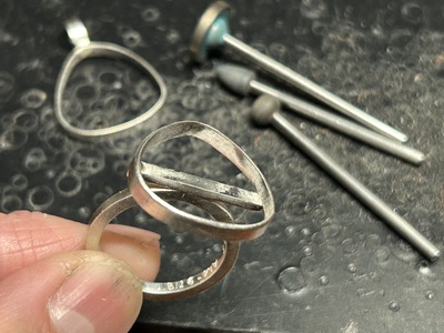 リング腕やペンダントの土台となる金属パーツを手に持った写真