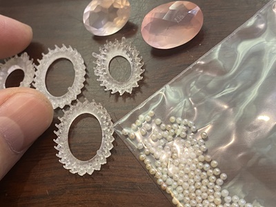 作業台に置かれた3Dプリント製の透明な樹脂枠、2つのローズクォーツ、そして袋に入った大量の極小ベビーパール。