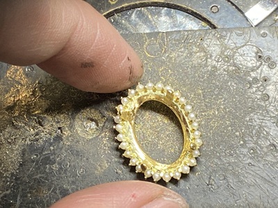 全てのベビーパールが金枠にセットされた状態のペンダントトップ。作業台の上で輝きを放っている。