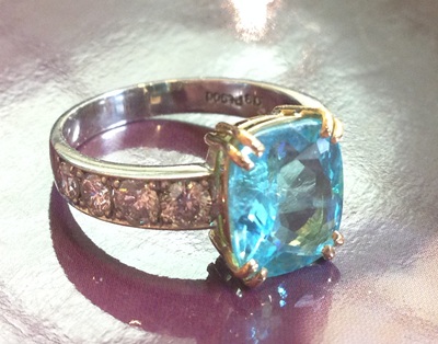 完成したパライバトルマリンリング、テーブル上に置かれた実物写真・内側にブランド刻印あり