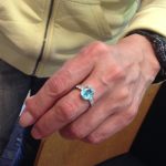 パライバトルマリンのアニバーサリーリングを着用した女性の手、実際の指へのフィット感と色の美しさを確認