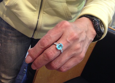 パライバトルマリンのアニバーサリーリングを着用した女性の手、実際の指へのフィット感と色の美しさを確認