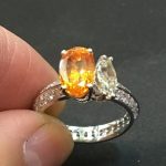 リングのアーム部分に小さなダイヤモンドを留めている手元の作業風景