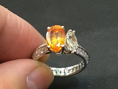 リングのアーム部分に小さなダイヤモンドを留めている手元の作業風景