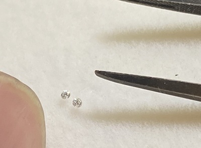 ピンセットで持たれた、非常に小さな2つのダイヤモンド。