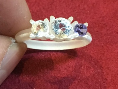 樹脂製のリング枠に実際の宝石3石を仮置きして確認している様子