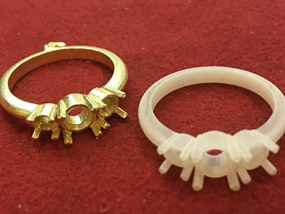 白い樹脂原型と鋳造されたゴールドのリング枠を並べて比較している写真