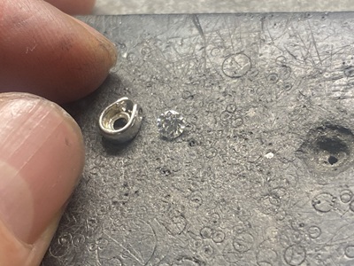 鋳造工程を経てプラチナ製になったペンダント枠と、横に置かれたダイヤモンド