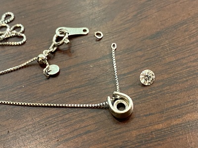 プラチナのペンダント枠にベネチアンチェーンを通し、可動域を確認する様子