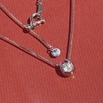 赤い背景の上で輝く、完成したプラチナ製馬蹄形ダイヤモンドペンダント。