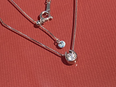 赤い背景の上で輝く、完成したプラチナ製馬蹄形ダイヤモンドペンダント。