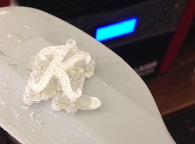 3Dプリンターから取り出した直後の、半透明な樹脂製のイニシャル「K」原型。