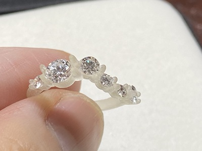 3Dプリントされた樹脂製のリング原型にダイヤモンドを仮置きして手に持った様子
