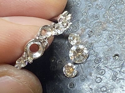 ピンセットでダイヤモンドをリングの爪にセットしようとしている様子