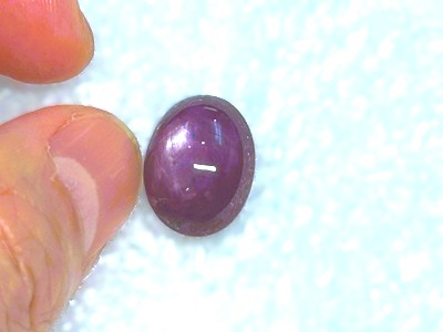 指で持たれた、艶やかで大粒のカボションカットルビー