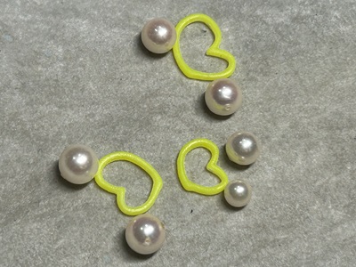 黄色の3Dプリント樹脂モデルの上に、あこや真珠を配置してレイアウトを確認している様子。