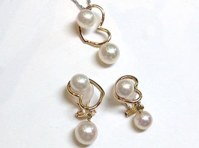 白い背景に並べられた、お揃いの蝶デザインの真珠イヤリングとペンダントのセット。