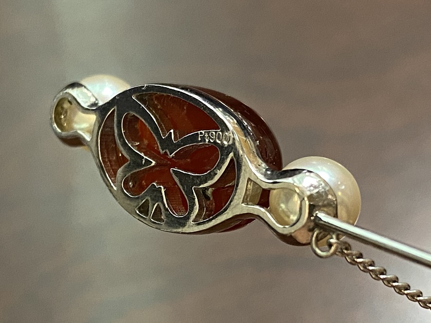 深紅のレッドアンバーと、その両サイドに白いあこや真珠を配した、完成したプラチナブローチ。