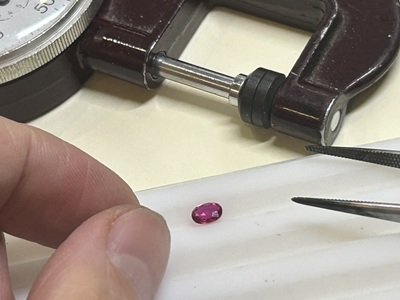 ピンク色の宝石を精密な測定器で測る様子