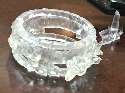 作業台の上に置かれた、光硬化3Dプリンターから出力されたばかりの透明なレジン樹脂製の龍リング原型