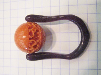 方眼紙の上に置かれた、紫色のワックスモデルとオレンジ色の彫刻入り珊瑚の珠。