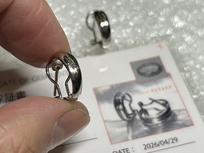 ラミネート加工された完成品の証明書とピアスの横に置かれた指。