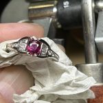 顕微鏡や工具が並ぶ作業台の上で、ピンセットやタガネを用いてリングの爪を倒し、ルビーとダイヤモンドを固定していく石留めの瞬間
