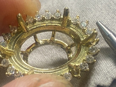 顕微鏡やルーペを使いながら、小さなK18の爪をタガネで一つずつ慎重に倒してメレダイヤモンドを固定する石留め工程。