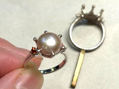 中央に大粒の湖水真珠、両サイドに鮮やかなオレンジサファイアが留められた完成品のリング