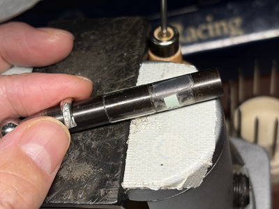 太さの異なる3種類の鉄製の芯棒（坊主）に、切断した指輪パーツをあてて半円のカーブを整えている手元。