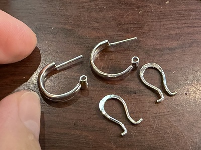 木のテーブルの上に並べられた、1.2cmのポストがしっかりと固定された2つのフープピアスと、取り外された2つのバネ金具。
