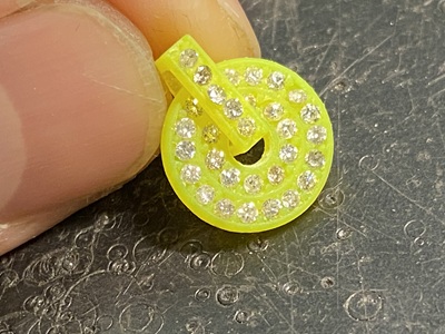 蛍光黄色の樹脂原型の小さな穴(石座)の一つひとつに、実際のメレダイヤモンドをピンセットで仮配置し、サイズや配置が寸分の狂いもなく一致しているかを確認しているクローズアップ手元写真。