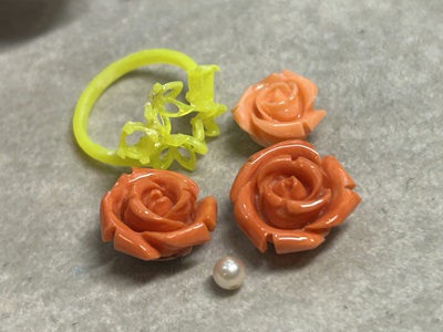 3Dプリンターで出力された黄色の樹脂製のリング枠原型と、実物の薔薇の珊瑚、ベビー真珠