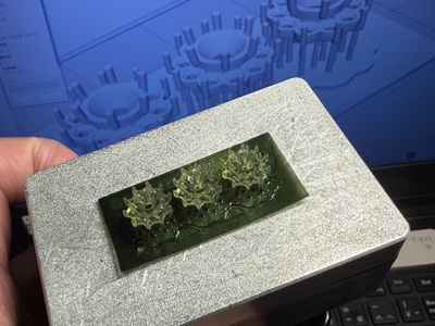 3Dプリンターの台座に整然と出力された、繊細な花の蕾のような形をした緑色の樹脂製原型3個