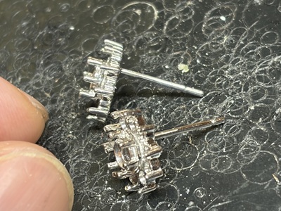 耐火作業台の上に置かれた、シャトンの裏側にまっすぐなピアスポスト（針）が溶接されたプラチナ枠2個
