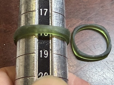 金属製のサイズ棒に樹脂リングを通し、18号の位置で正確にサイズを計測している様子