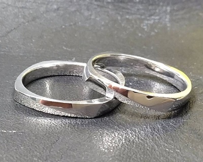 黒い背景の上に重ねて置かれた、磨き上げられた男性用と女性用のプラチナペアリング