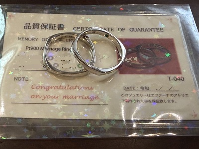 ラミネート加工された「ジュエルエファーナ品質保証書」の上に重なるように置かれたプラチナ結婚指輪2本