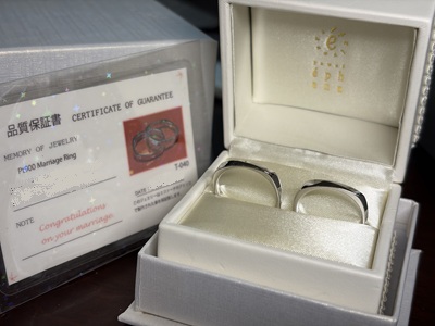 ジュエルエファーナのロゴが入った白い専用リングケースにセットされた2本の結婚指輪と保証書