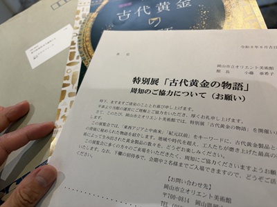 岡山市立オリエント美術館からの案内状「特別展『古代黄金の物語』周知のご協力について（お願い）」を手にする様子