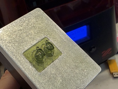 3Dプリンターのプラットフォーム上に生成された緑色の樹脂パーツ