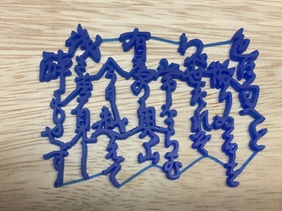 木目調の作業台の上に置かれた「いろは歌」の青い3Dプリントサンプル