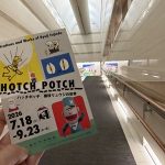 高松市美術館のロングスロープで特別展「ハッチポッチ 藤枝リュウジの世界」のチラシを手にする様子