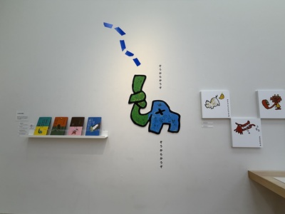 白を基調としたギャラリーの壁面に飾られたユニークなゾウのグラフィックと絵本作品
