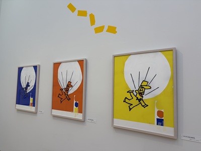 同じイラスト構図で背景色が青・オレンジ・黄と異なる3枚の額装作品