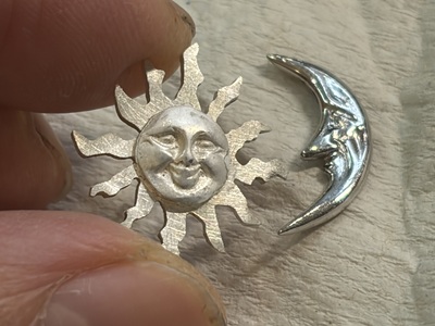 太陽の土台に太陽の顔がロウ付けされ、隣に月のパーツがある様子。