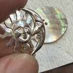 シェルの穴にシルバーのSun & Moonを差し込み、裏から固定しようとしている様子。
